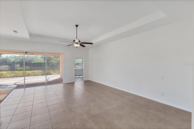 spare room with ceiling fan, light tile patterned floors, and a tray ceiling