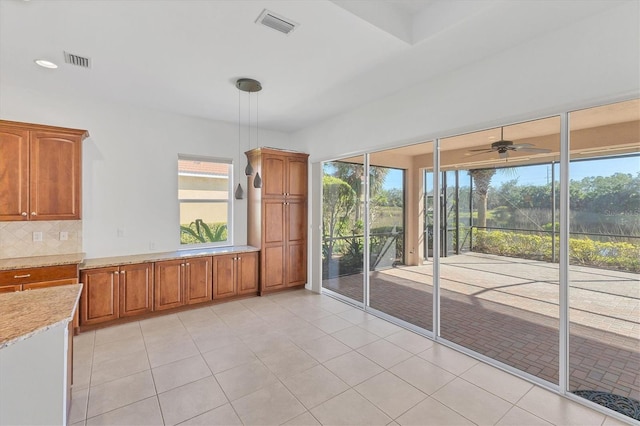 interior space with pendant lighting, tasteful backsplash, a healthy amount of sunlight, and light tile patterned flooring