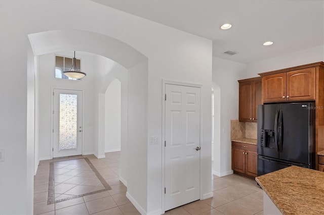 kitchen with decorative backsplash, light tile patterned floors, fridge with ice dispenser, and hanging light fixtures