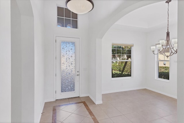 entrance foyer featuring light tile patterned floors, a wealth of natural light, and a notable chandelier