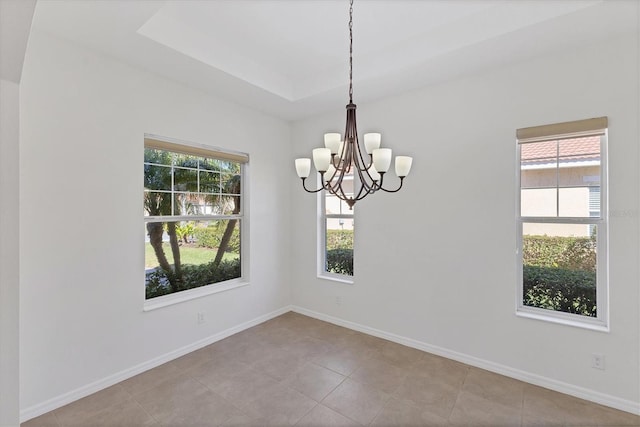 unfurnished room featuring a raised ceiling, a wealth of natural light, light tile patterned floors, and a notable chandelier