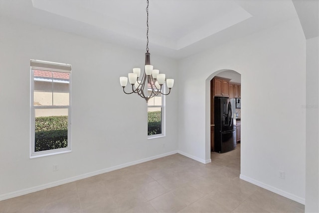 unfurnished room with a raised ceiling, light tile patterned floors, and an inviting chandelier