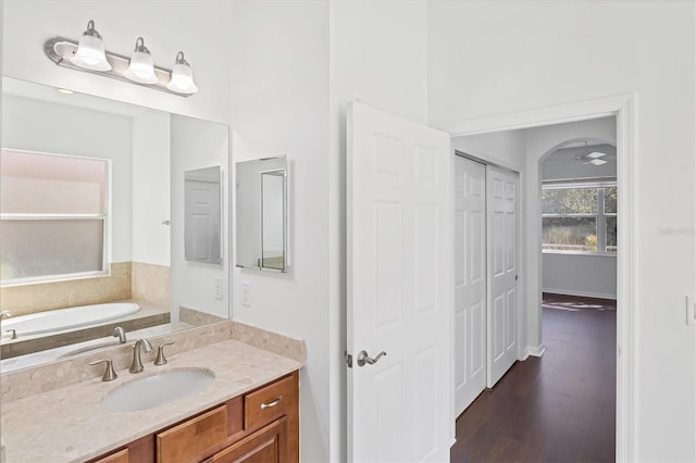 bathroom featuring ceiling fan, a bathtub, vanity, and wood-type flooring