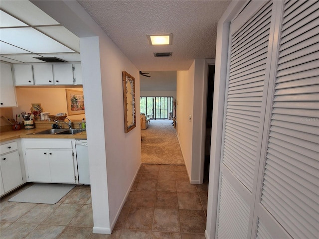 hall featuring a textured ceiling, sink, and light tile patterned floors