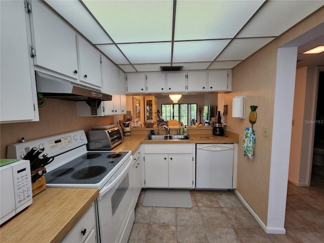 kitchen featuring white cabinets, a paneled ceiling, light tile patterned flooring, sink, and white appliances