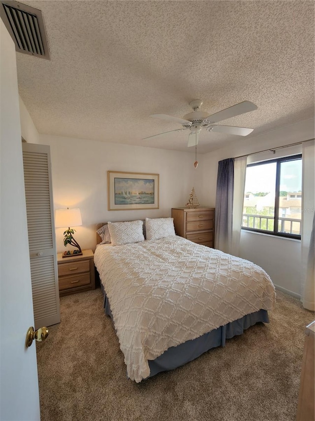 bedroom with ceiling fan, a textured ceiling, and carpet floors