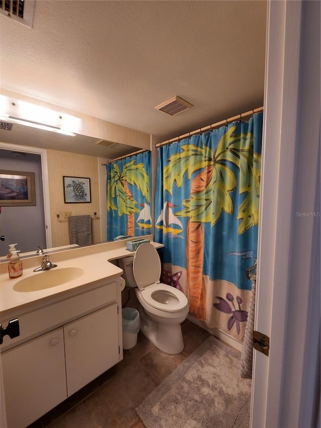 bathroom with a textured ceiling, walk in shower, toilet, vanity, and tile patterned floors