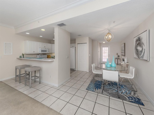 kitchen with kitchen peninsula, white cabinets, crown molding, a breakfast bar, and an inviting chandelier