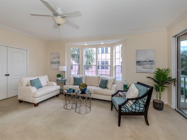 living room featuring ceiling fan, a healthy amount of sunlight, ornamental molding, and light colored carpet