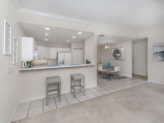 kitchen with crown molding, a breakfast bar, light colored carpet, white cabinetry, and white appliances