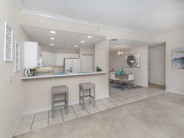 kitchen with a breakfast bar area, light tile patterned floors, a peninsula, ornamental molding, and white appliances