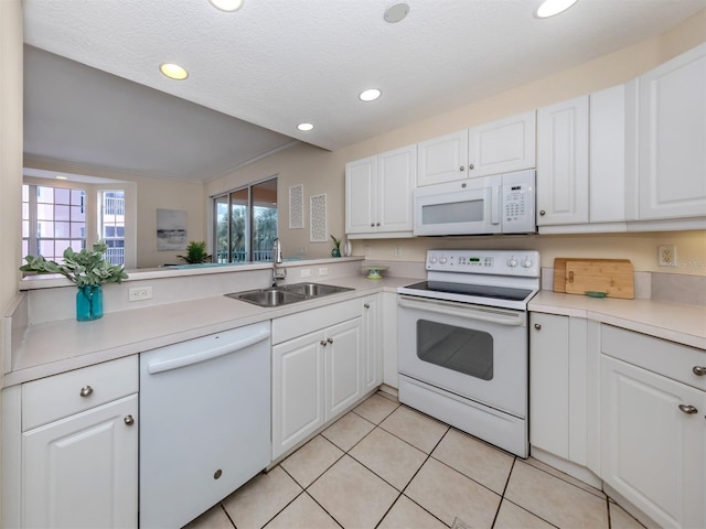 kitchen with white appliances, light countertops, white cabinetry, a sink, and light tile patterned floors