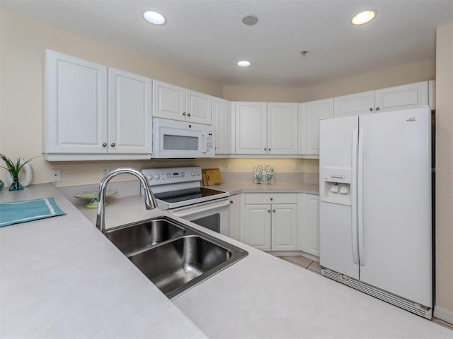 kitchen with light countertops, a sink, white cabinets, recessed lighting, and white appliances