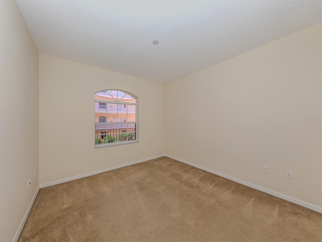 empty room featuring baseboards and light carpet