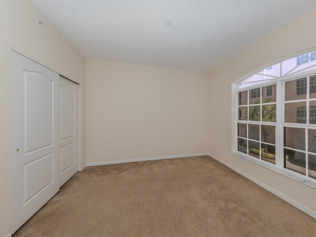 unfurnished bedroom with light colored carpet, baseboards, and a closet