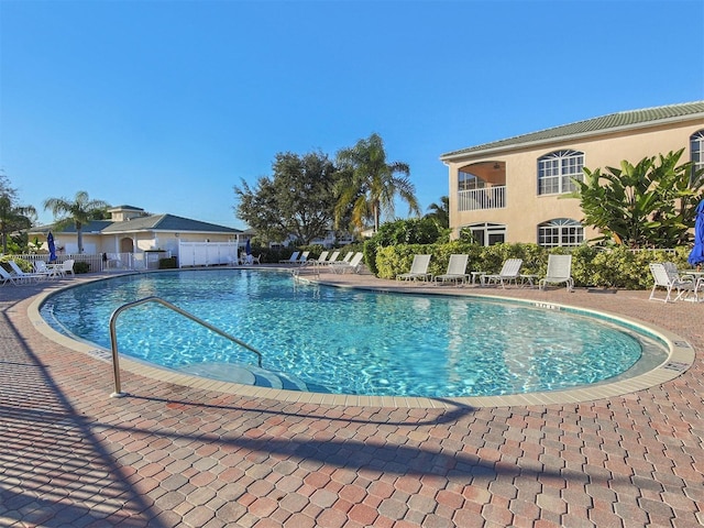community pool with fence and a patio