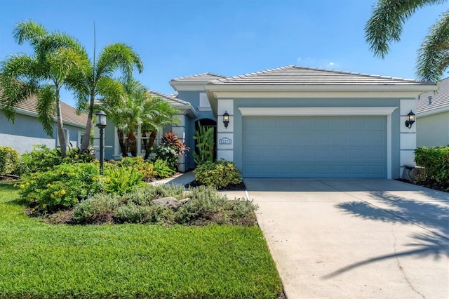 view of front of house featuring a garage, driveway, a front yard, and stucco siding