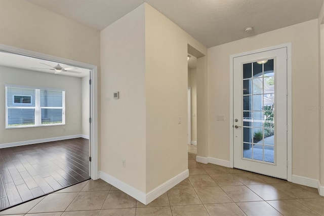 doorway featuring ceiling fan, a textured ceiling, light wood-type flooring, and a healthy amount of sunlight