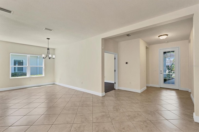 interior space featuring a notable chandelier, light tile patterned floors, and a textured ceiling