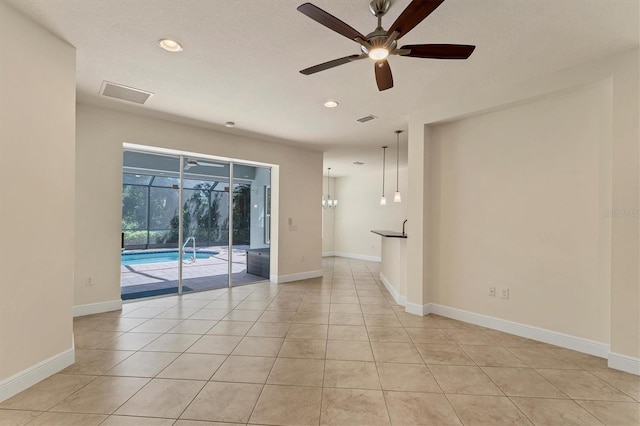 tiled empty room featuring ceiling fan and a textured ceiling