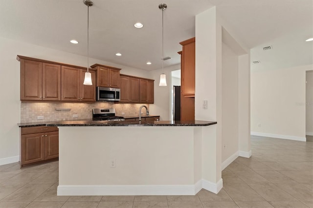 kitchen with decorative backsplash, dark stone countertops, decorative light fixtures, sink, and stainless steel appliances