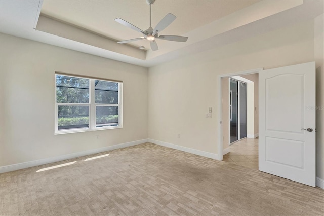 carpeted spare room featuring ceiling fan and a tray ceiling