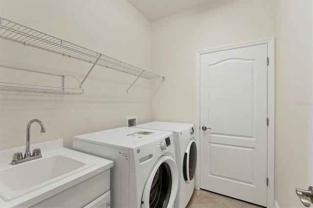 laundry area featuring washer and clothes dryer, sink, and light tile patterned floors