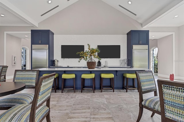 kitchen with stainless steel built in fridge, vaulted ceiling, and blue cabinets