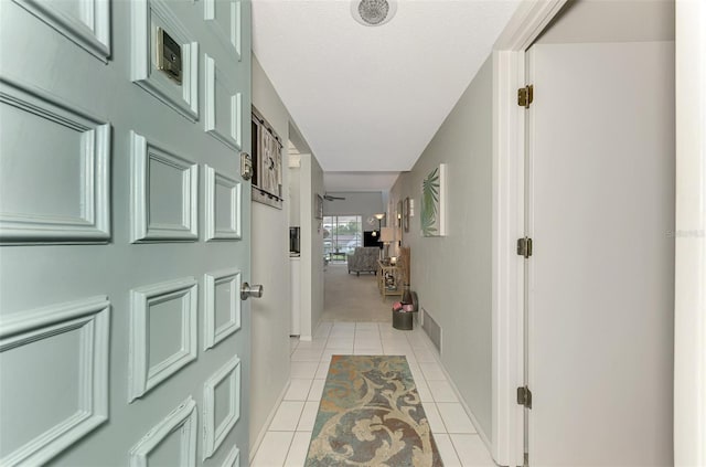 hall featuring light tile patterned flooring and a textured ceiling