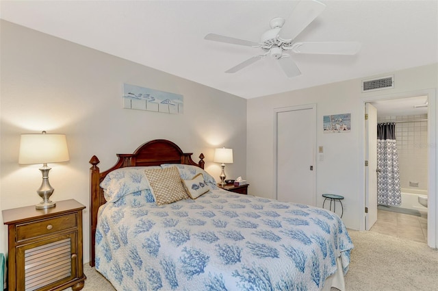 carpeted bedroom with ensuite bathroom and ceiling fan