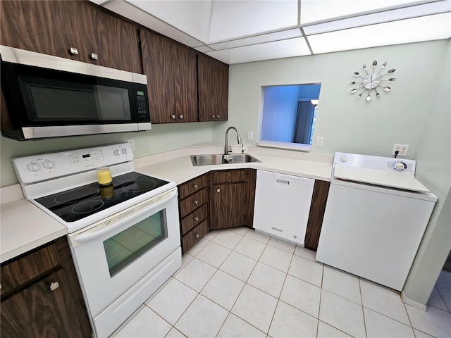 kitchen with white appliances, sink, light tile patterned flooring, washer / dryer, and dark brown cabinets