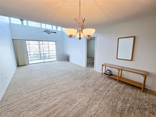 empty room featuring ceiling fan with notable chandelier and carpet flooring