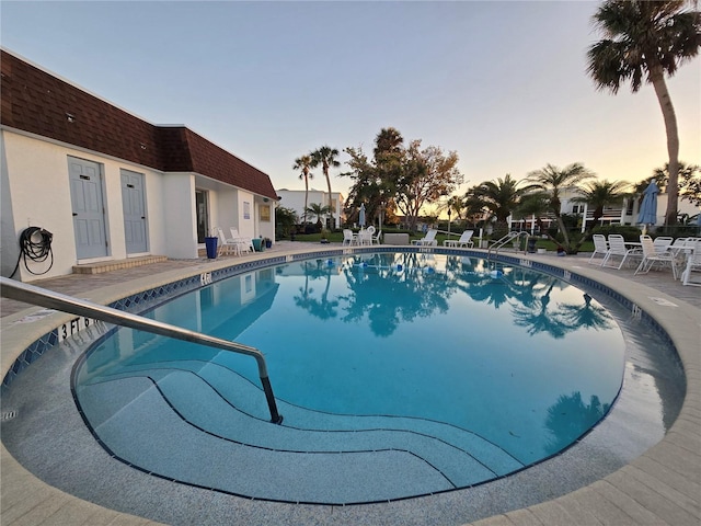 pool at dusk featuring a patio area