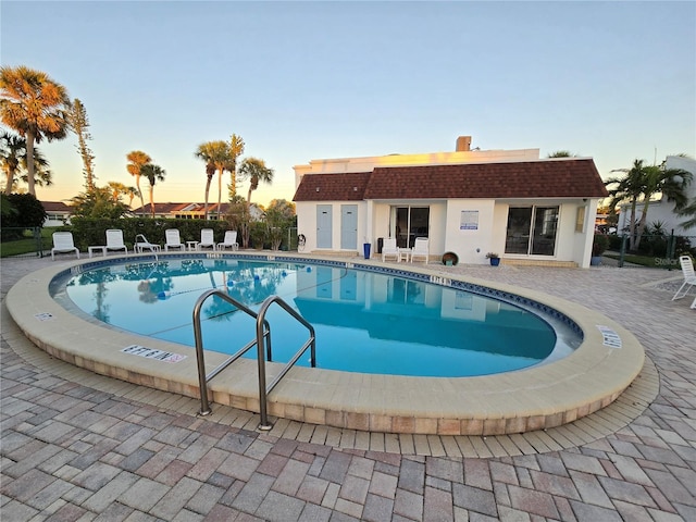 pool at dusk with a patio area