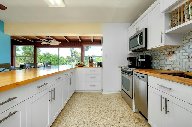 kitchen featuring white cabinetry, stainless steel appliances, a wealth of natural light, and wooden counters