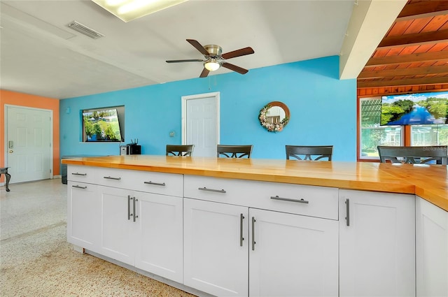 kitchen with white cabinets, butcher block counters, beamed ceiling, and a kitchen bar