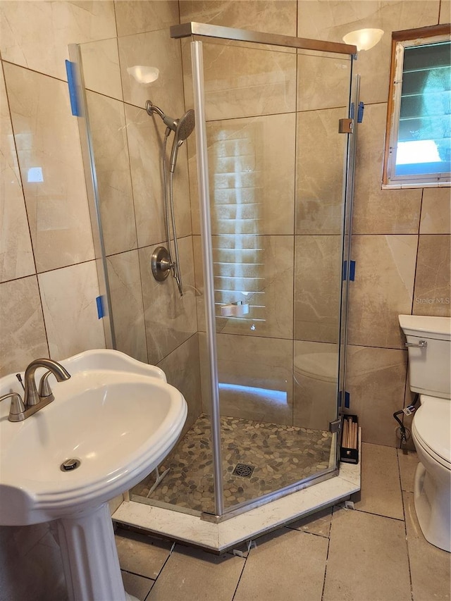 bathroom featuring tile walls, tile patterned floors, toilet, and an enclosed shower