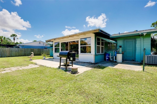 back of property with a yard, a patio area, and a sunroom