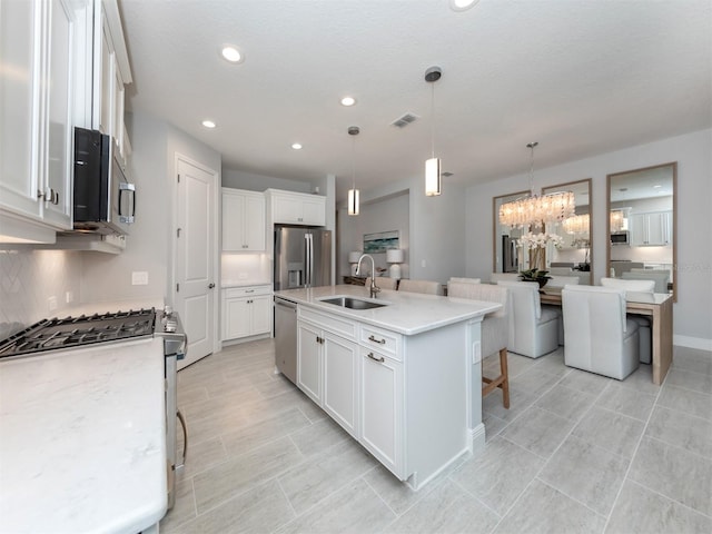 kitchen featuring an island with sink, stainless steel appliances, a kitchen bar, and white cabinetry