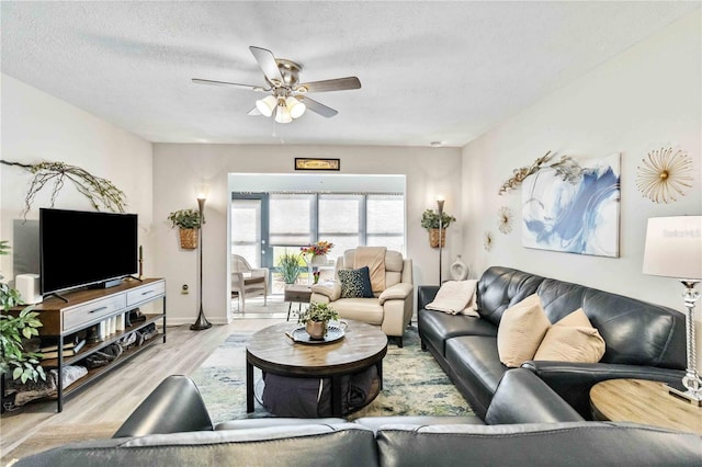 living room featuring light hardwood / wood-style floors, a textured ceiling, and ceiling fan