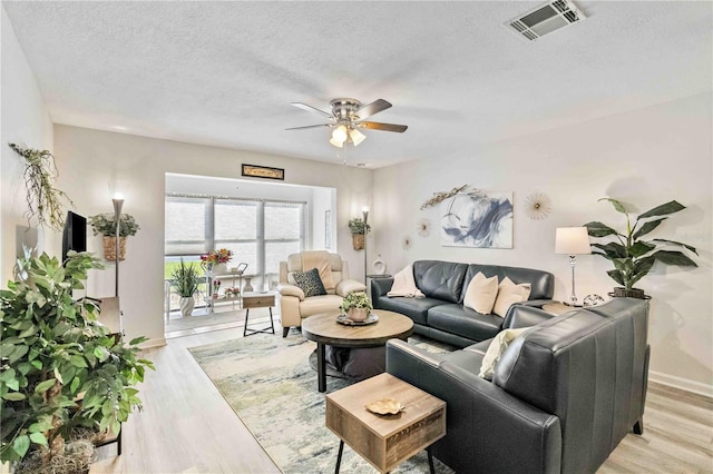 living room with light hardwood / wood-style floors, a textured ceiling, and ceiling fan