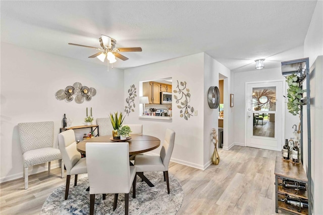 dining space featuring a textured ceiling, light hardwood / wood-style floors, and ceiling fan