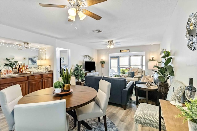 dining area with sink, light wood-type flooring, and ceiling fan