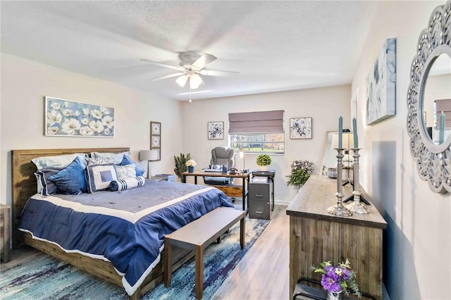 bedroom with ceiling fan, a textured ceiling, and hardwood / wood-style floors