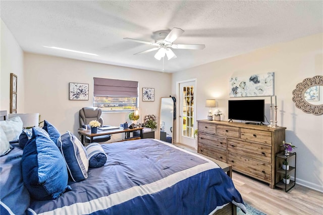 bedroom with light hardwood / wood-style flooring, a textured ceiling, and ceiling fan