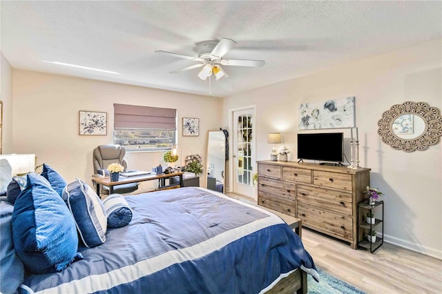 bedroom with a textured ceiling, light wood-type flooring, and ceiling fan