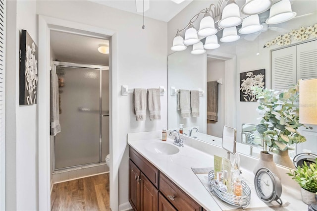 bathroom featuring vanity, hardwood / wood-style flooring, toilet, and a shower with door