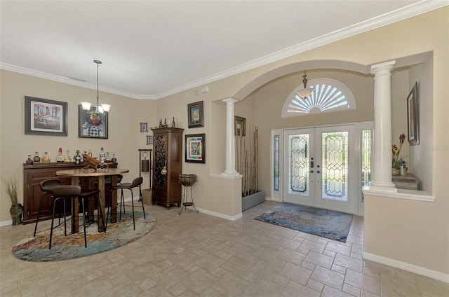 entryway with french doors, an inviting chandelier, and crown molding