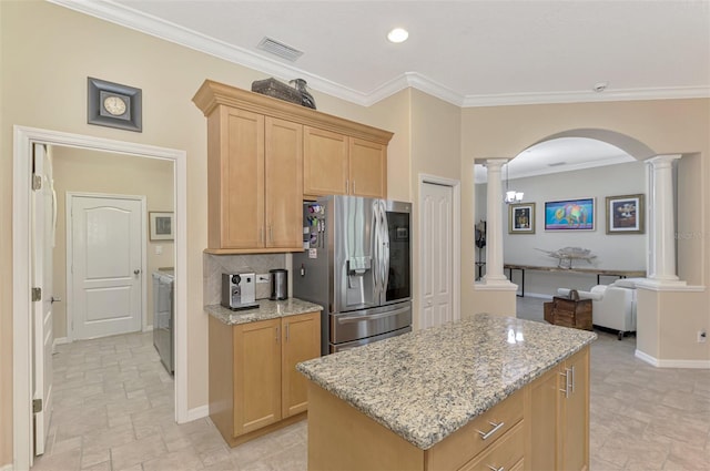 kitchen with a center island, crown molding, stainless steel refrigerator with ice dispenser, light stone countertops, and separate washer and dryer