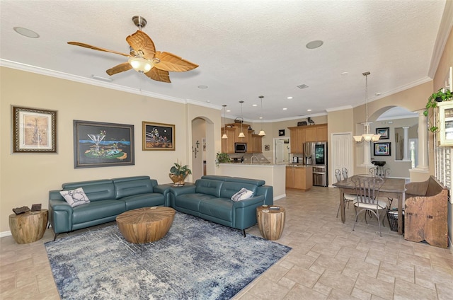 living room with ceiling fan with notable chandelier, ornamental molding, and a textured ceiling